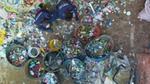 Workers sort mixed plastic waste into large color-coded bins at a recycling facility