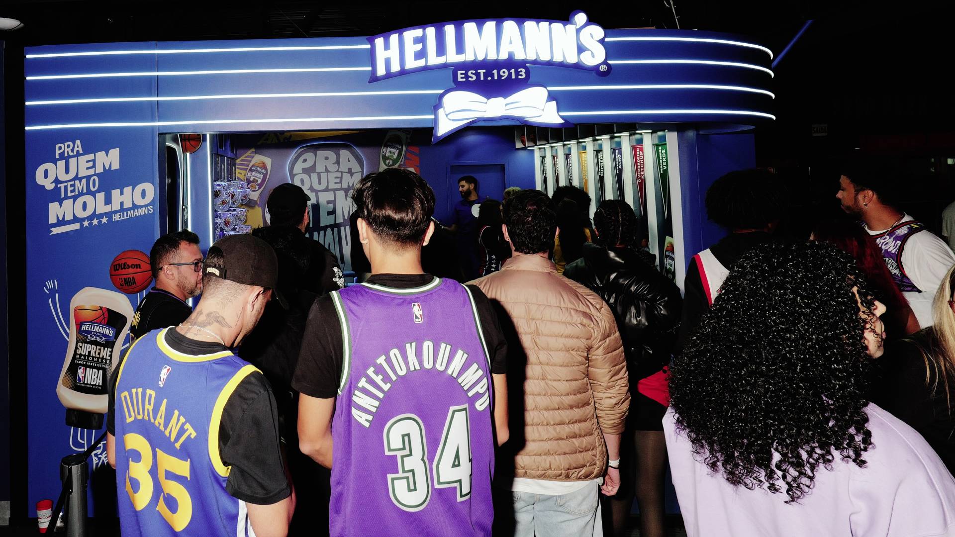 A group of young basketball fans wearing NBA team shirts enter a Hellmann’s sponsored event