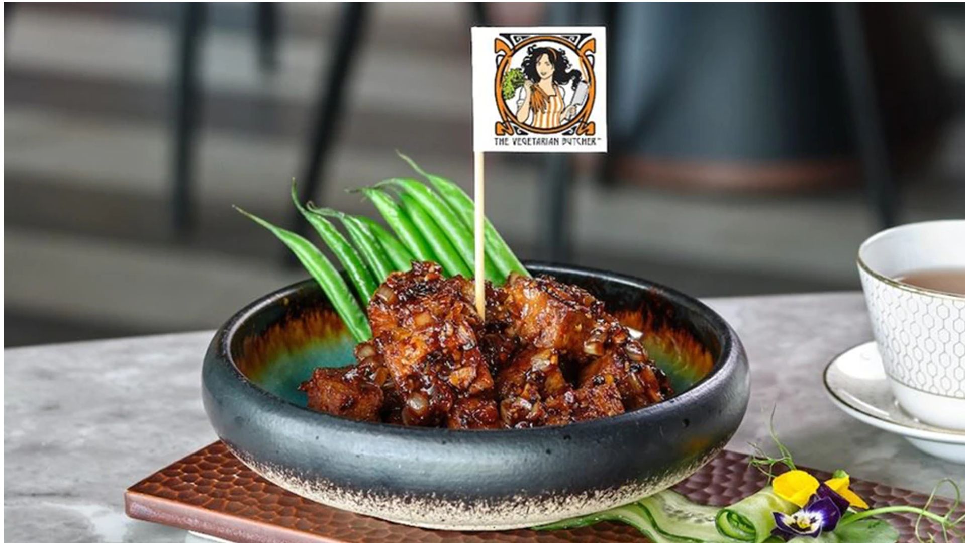 Sticky plant-based meat on a plate with The Vegetarian Butcher flag on it