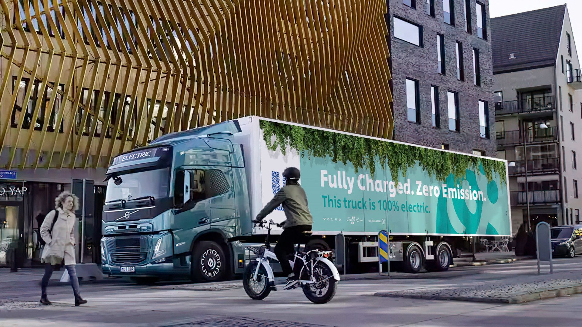An illustration of Unilever’s first electric truck driving through a town in the Netherlands. Text on the side reads: Fully charged. Zero emissions. This truck is 100% electric.