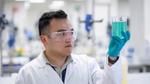 Image of a Unilever scientist in a lab looking at a glass of blue liquid.