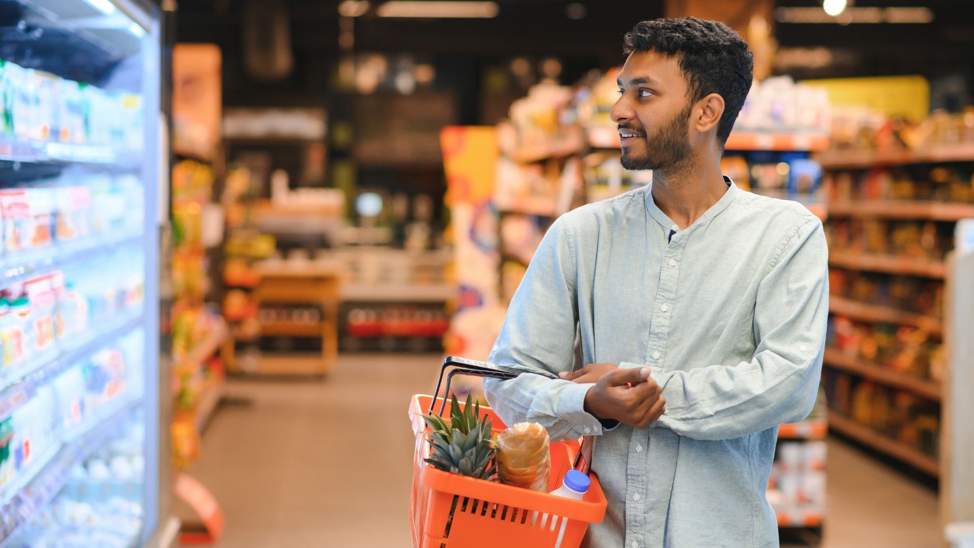 Man shopping in a grocery store with a basket.