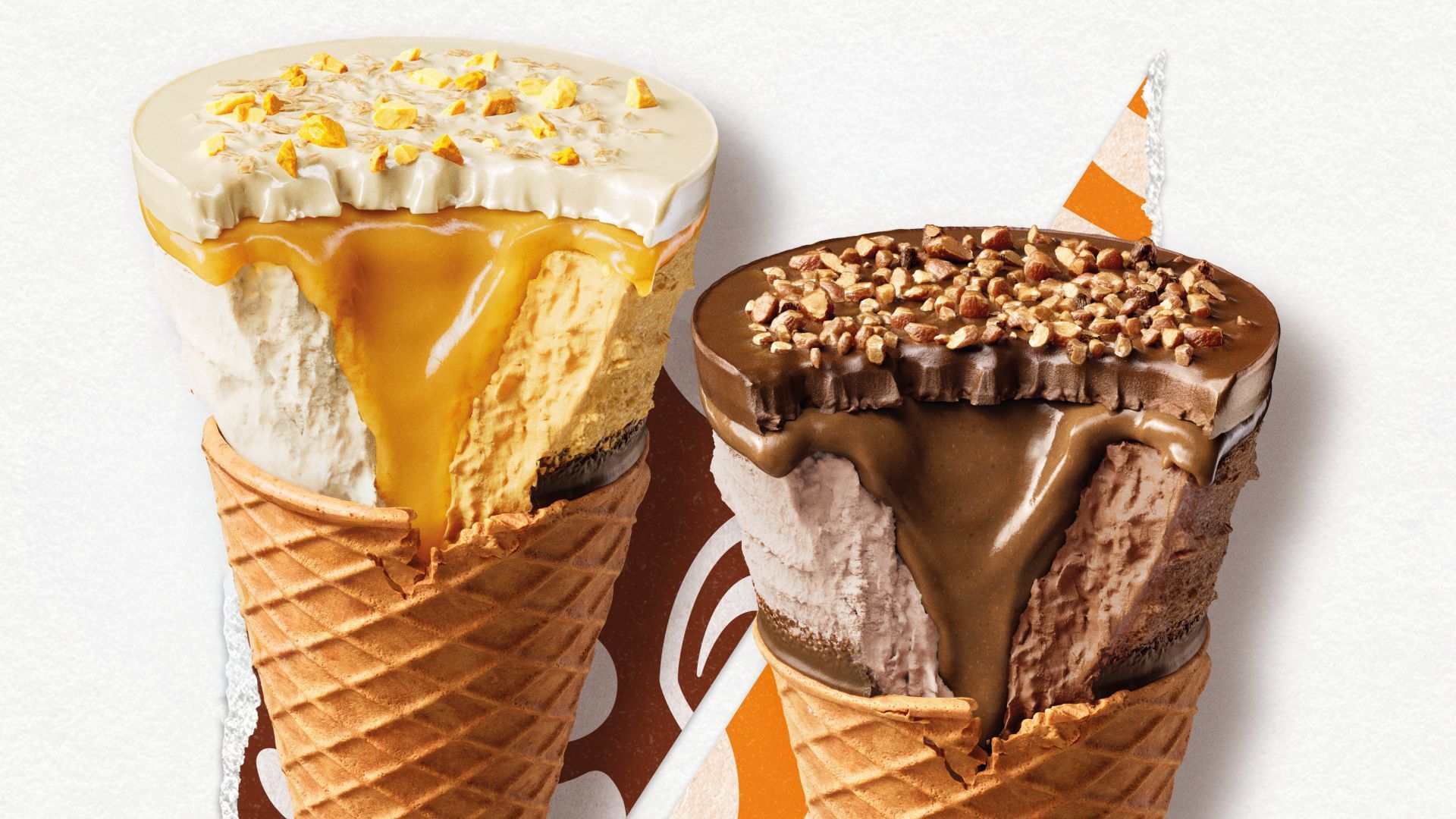 Cornetto Max’s Mango and Vanilla cone and Hazelnut and Chocolate cone sitting side by side. Both are partially unwrapped, and a bite has been taken out of each to show the thickness of each cone’s chocolatey disc top, sauces and ice cream.
