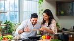 Couple cooking together in a kitchen with fresh vegetables.