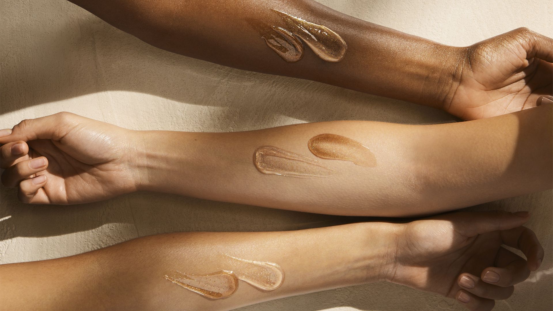 Three forearms of different skin tones displayed horizontally, each with two swatches of Vaseline skincare product in shades matching the skin tone.