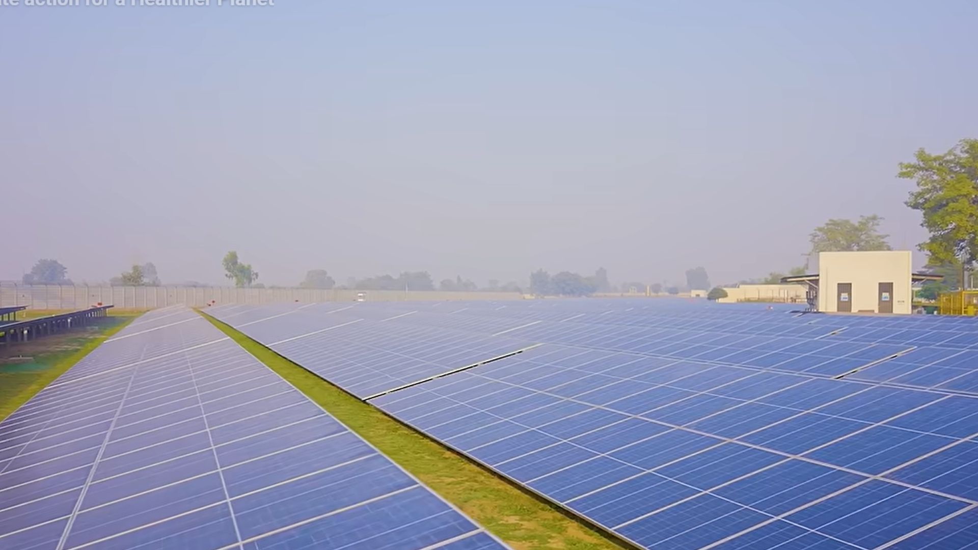 Large solar panel farm stretching across open land under a clear sky.