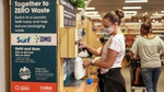 Woman filling a plastic bottle from an in-store refill machine that dispenses Surf and OMO products.