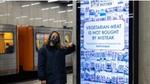 Woman in a face mask in an underground station leaning against a Vegetarian Butcher billboard