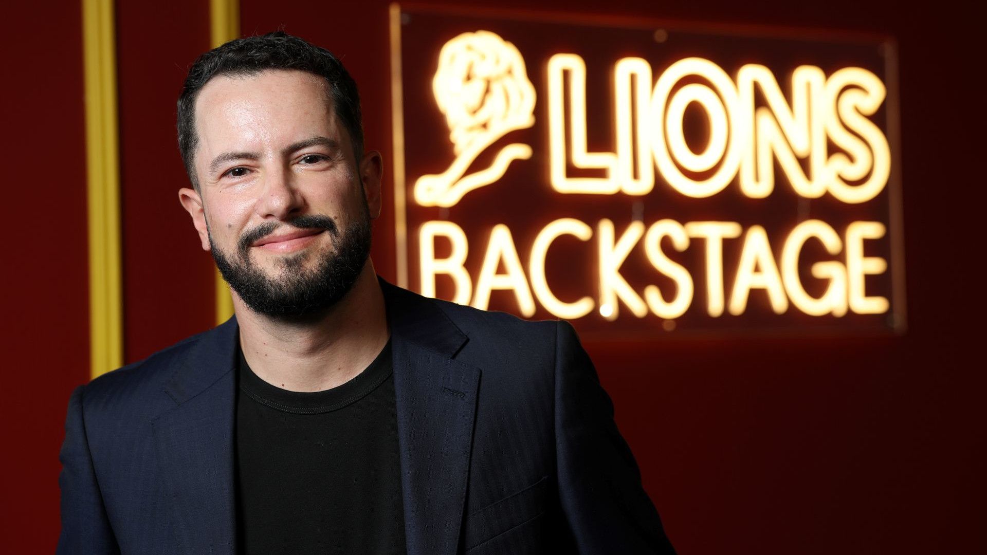 Leandro Barreto at Cannes Lions 2026 in front of a  ‘Lions backstage’ neon sign.