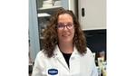 A photo of a scientist who worked on the Vaseline Verified campaign. A white woman with curly hair and glasses.