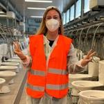 Deniz standing in front of a row of toilets in a warehouse.
